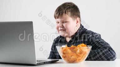 小胖男孩吃薯片，用笔记本电脑看动画片